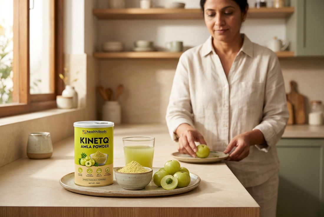 Healthibuds Amla Powder tin, juice and fresh Amla on a tray as a woman prepares fruit in a home kitchen.
