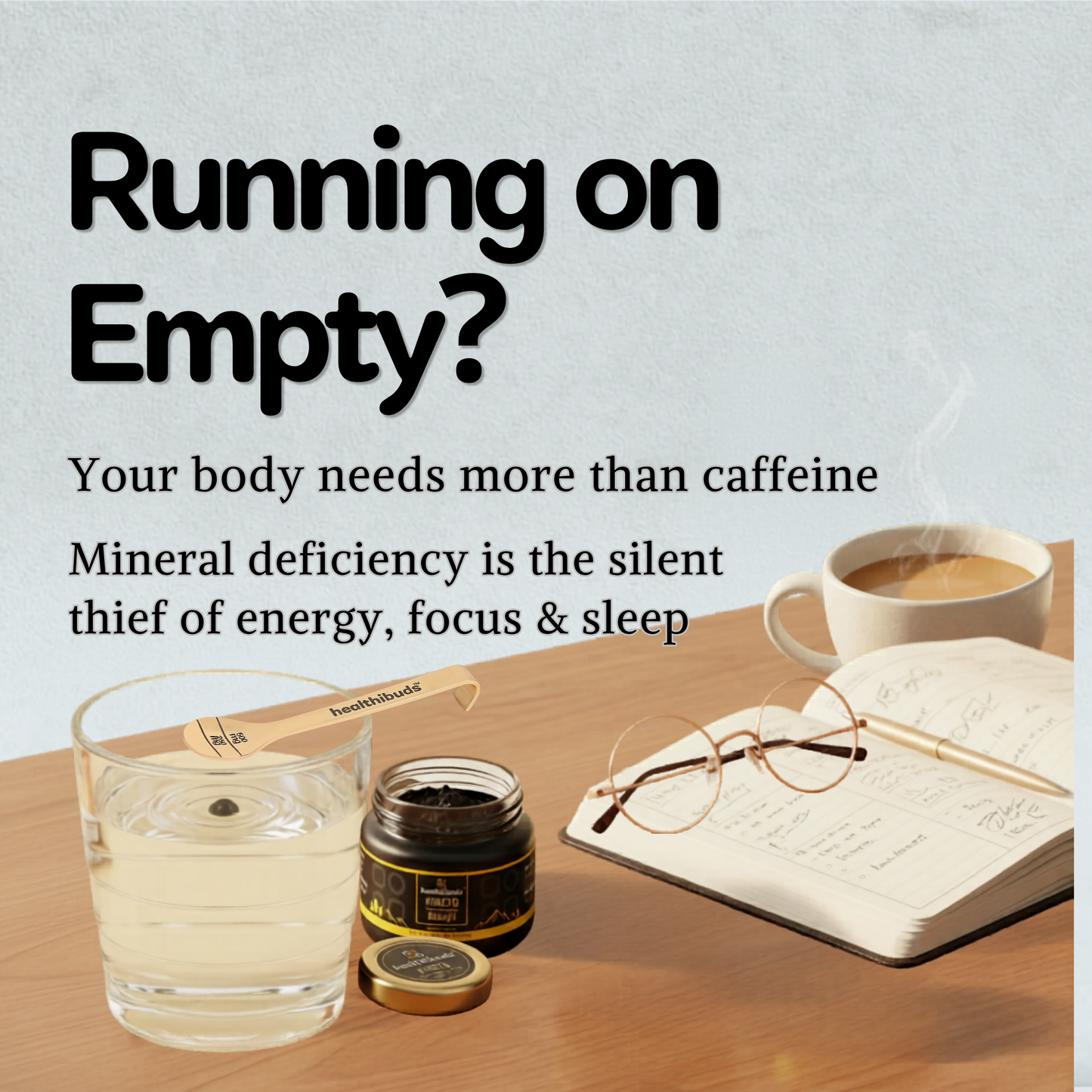 A wellness-themed promotional graphic with the text 'Running on Empty?' and supporting copy about mineral deficiency and lack of energy. The scene shows a glass of pale yellow liquid, a small jar with its lid off, a wooden spoon labeled 'Selenium', an open notebook with glasses on top, and a cup of coffee on a wooden table against a pale blue background.