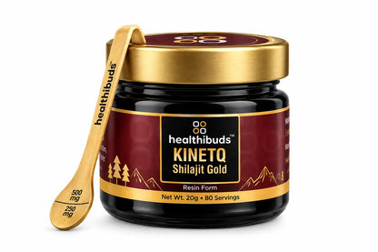 A jar of Healthbuds Kinetq Shilajit Gold resin form, featuring a dark maroon label with gold accents and a gold lid, shown alongside a wooden measuring spoon on a white background.