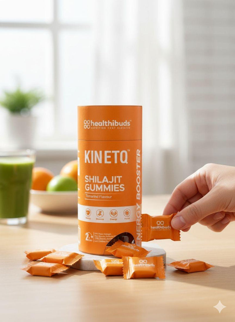 Hand picking a Healthibuds Kinetiq Shilajit Gummies package on a wooden table with a blurred background.