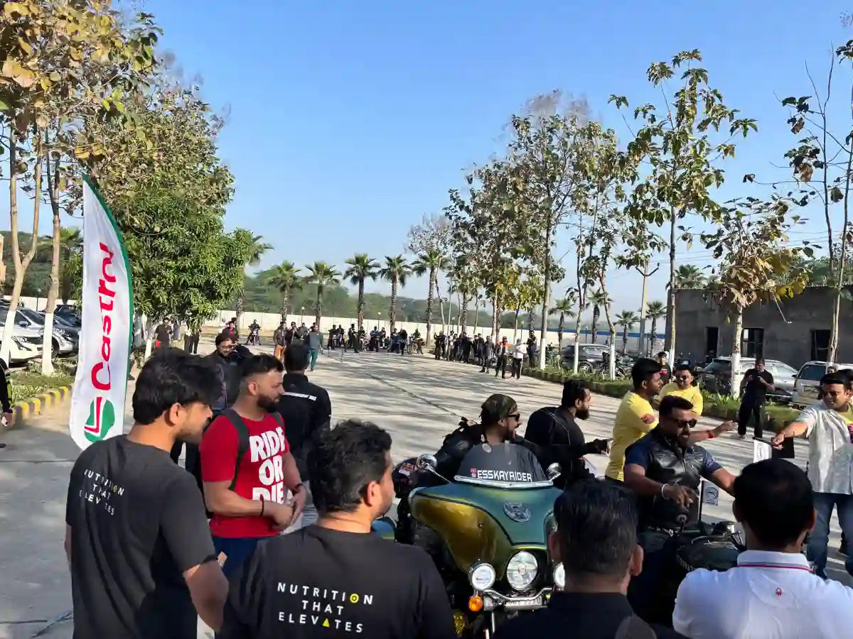 Group of people gathered around a motorcycle with a clear sky and trees in the background