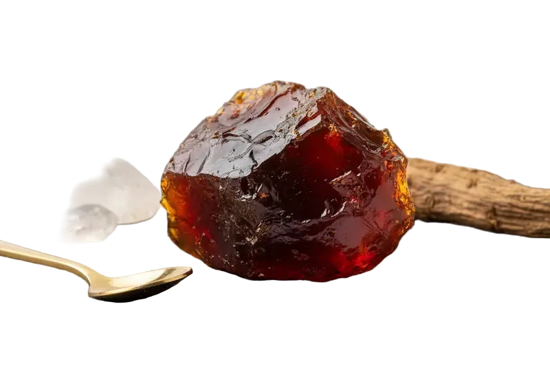 Gummy bear on a black slate with a spoon, crystals, and other items on a white background